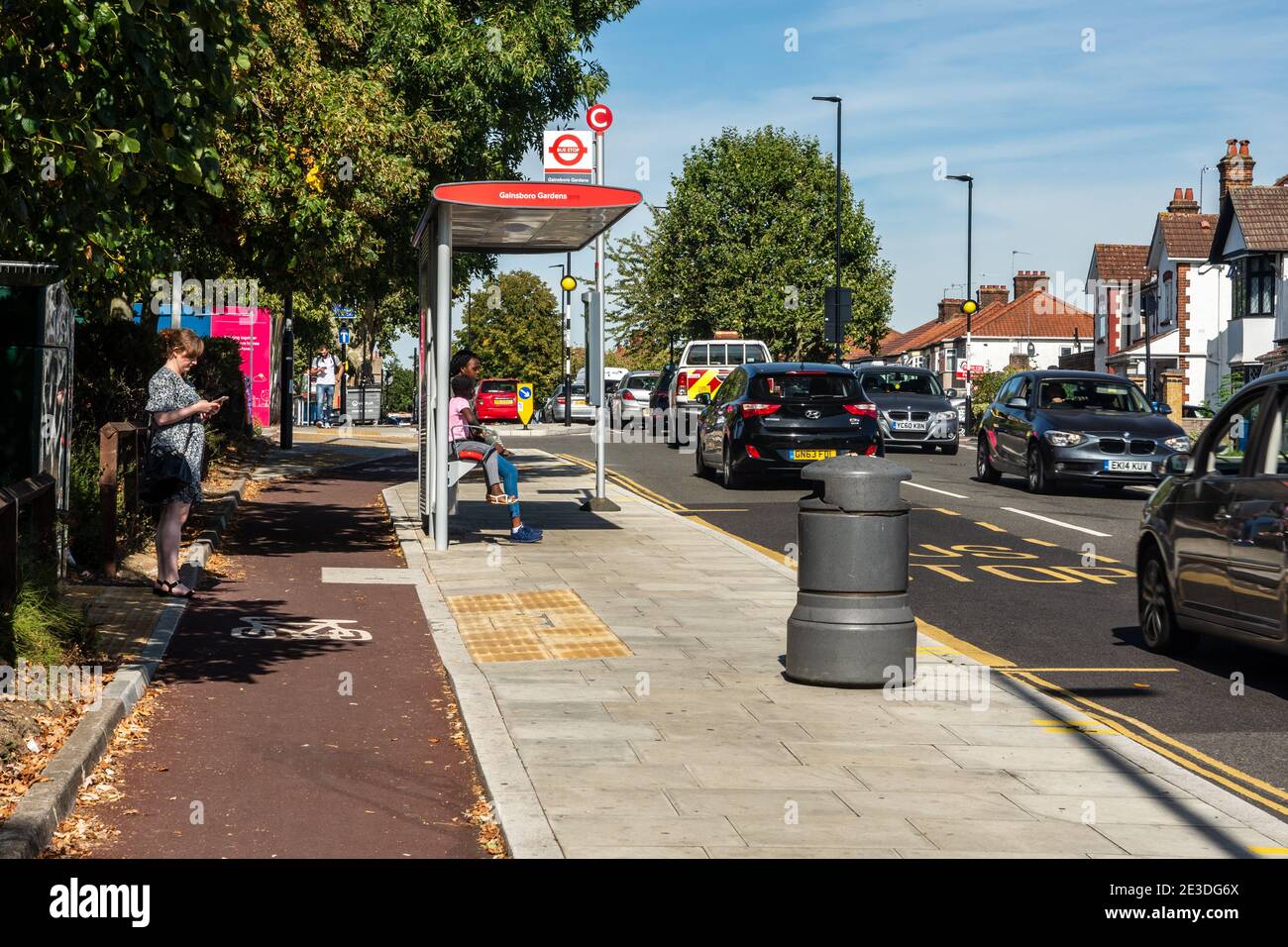 Los pasajeros esperan en una "parada de autobús flotante" en la ruta de una nueva pista de ciclismo protegida en Harrow, Londres. Foto de stock