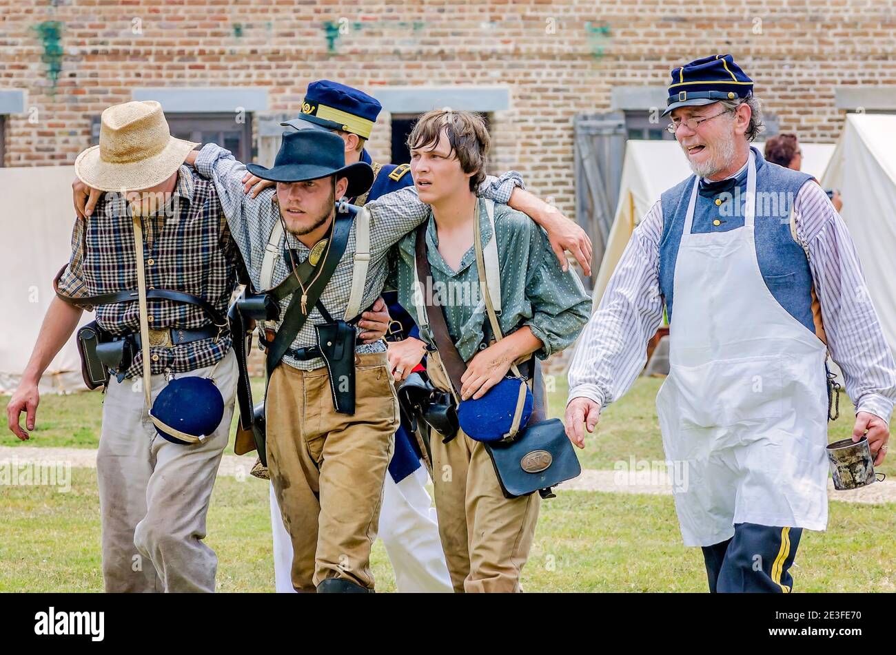 Los renactores de la Guerra Civil que representan al Ejército Confederado ayudan a un soldado herido en Fort Gaines durante una reconstrucción de la 150ª Batalla de Mobile Bay. Foto de stock