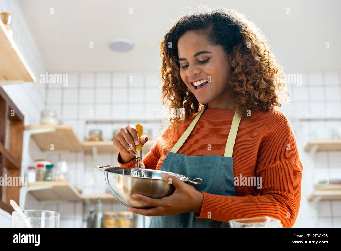 Joven afroamericana disfrutando de cocinar en la cocina mientras quedarse en casa Foto de stock