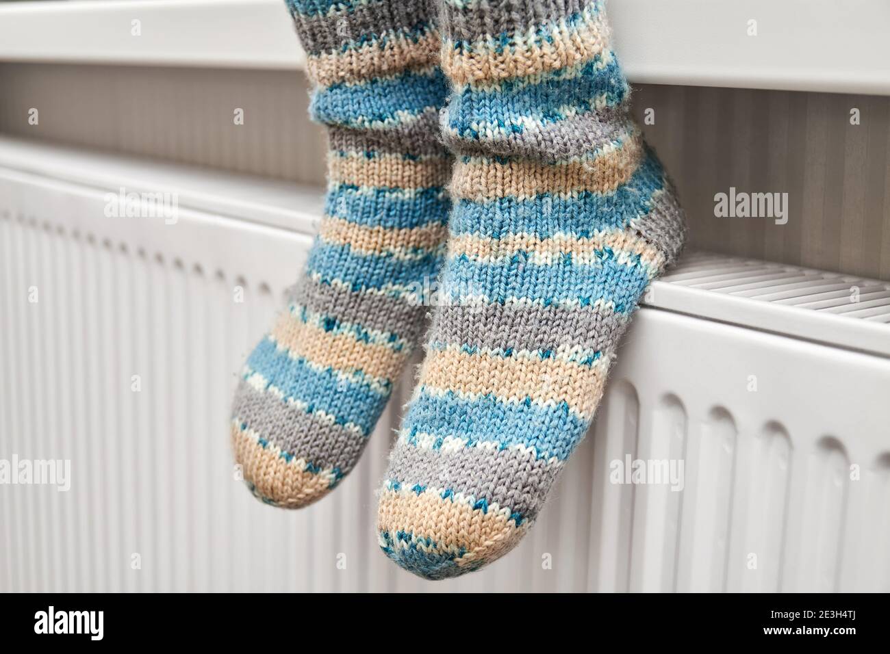 Una chica con calcetines de lana azul calienta los pies el radiador  Fotografía de stock - Alamy