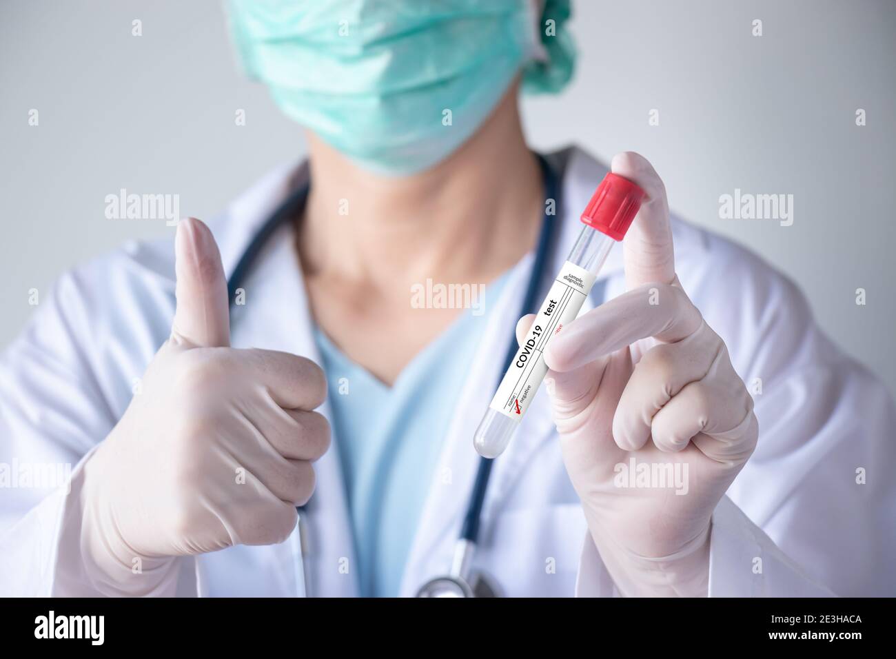 Prueba de coronavirus COVID-19. Doctor mano sosteniendo tubo de prueba de infección con muestra de secreción nasal del paciente para el resultado negativo etiqueta y pulgar hacia arriba gesto Foto de stock