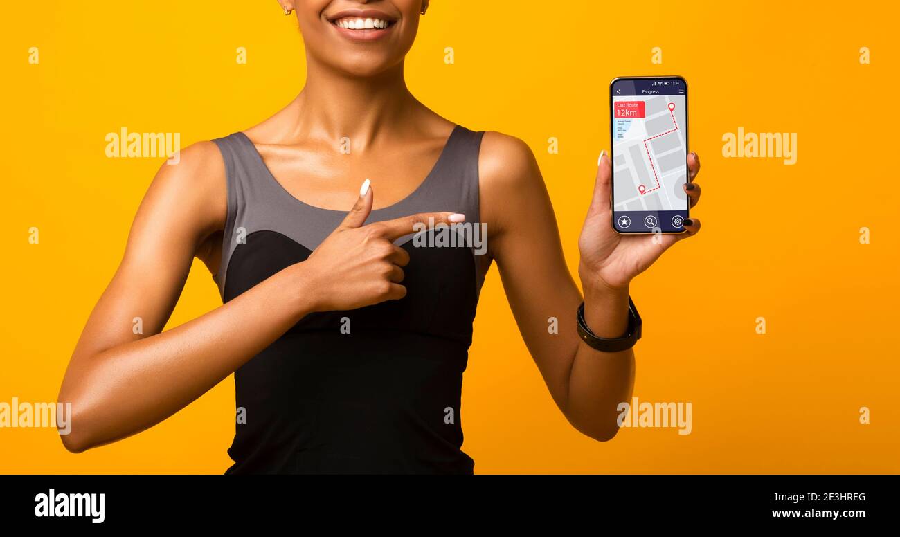 Mujer Negra mostrando teléfono con aplicación de contador de pasos, fondo amarillo Foto de stock