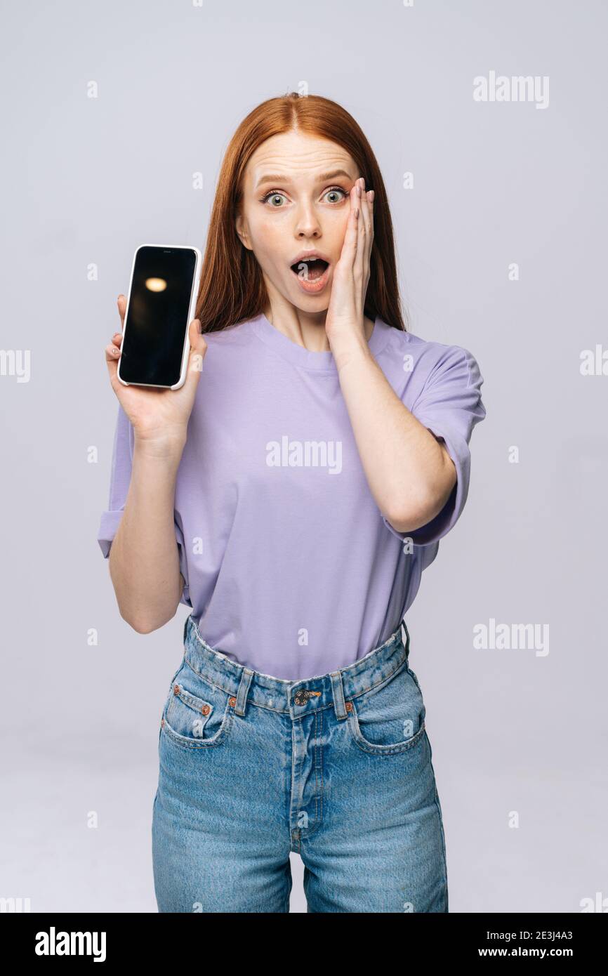 Una mujer joven molesta con ropa elegante que sostiene el teléfono celular  con pantalla móvil vacía en negro Fotografía de stock - Alamy