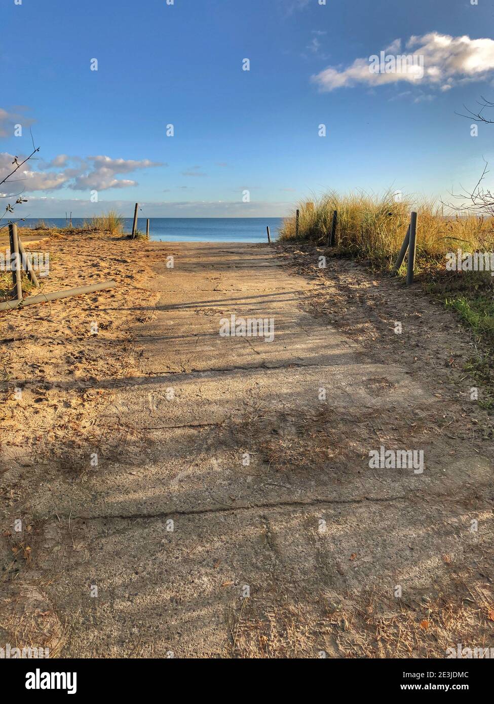 camino que conduce a una playa de arena con cielo azul y.. pocas nubes Foto de stock