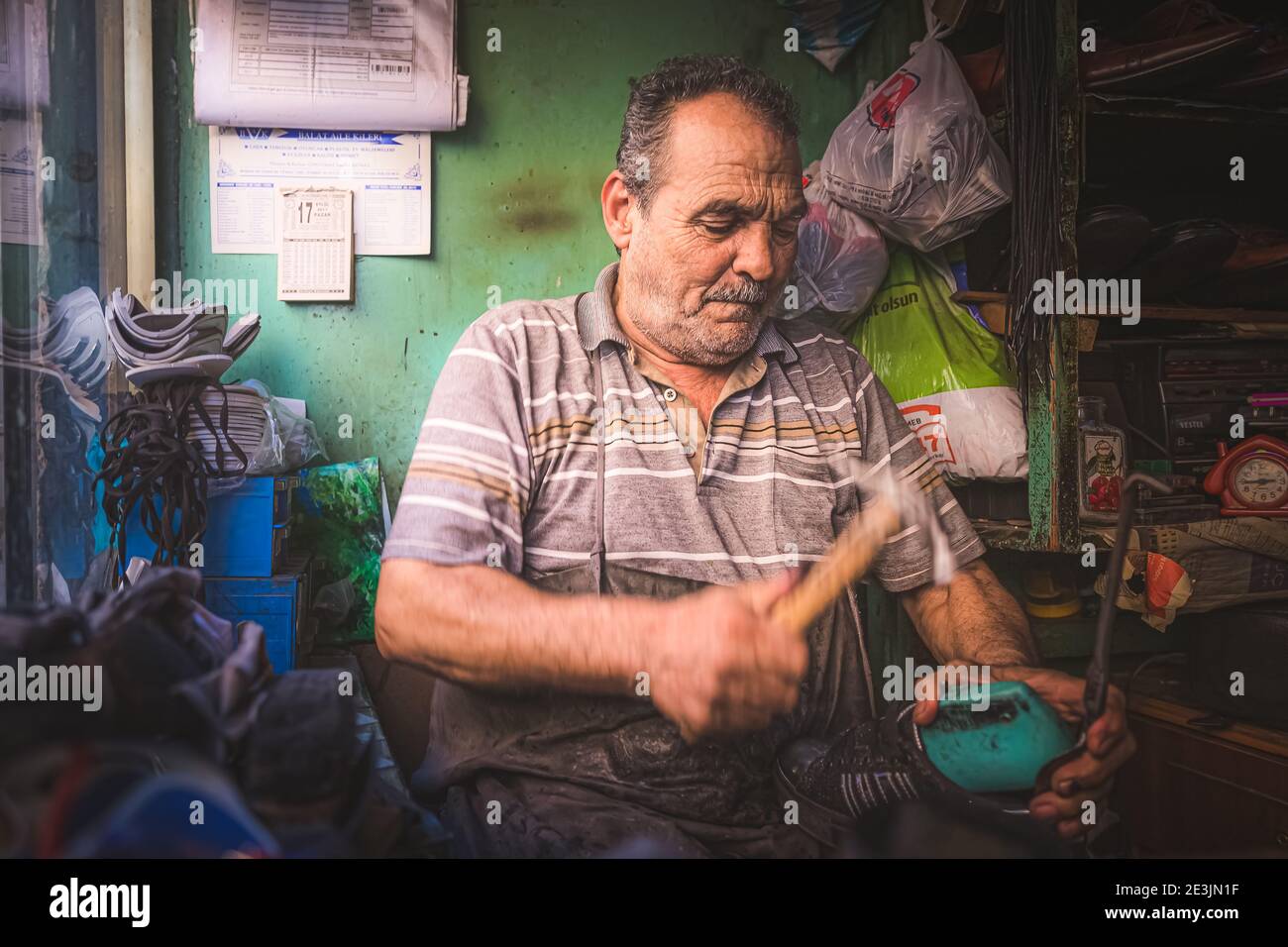 Estambul, Turquía - Septiembre 17 2017: Un retrato ambiental de un zapatero turco local reparando un zapato de su taller en el barrio de Estambul Foto de stock