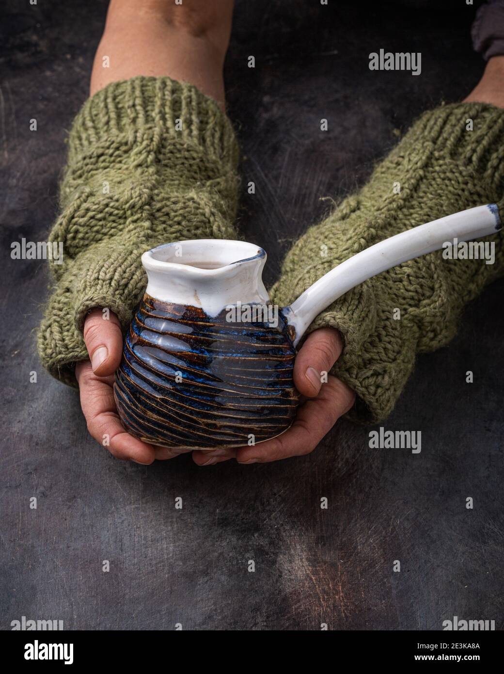 Taza hecha a mano en manos femeninas, foto oscura. Foto de stock