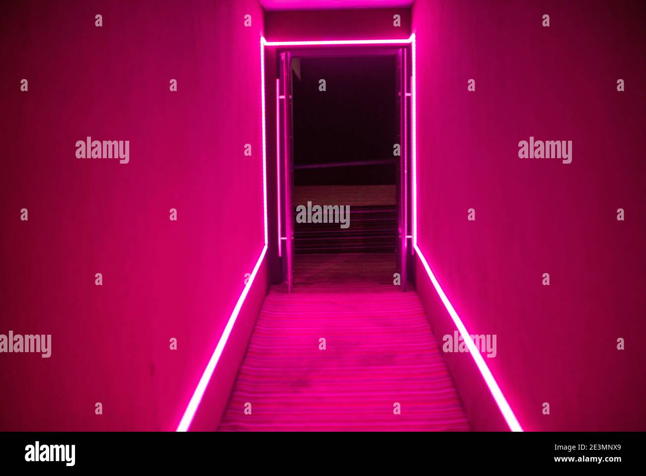 Colores de neón rosa muy iluminados en el interior de la habitación Foto de stock