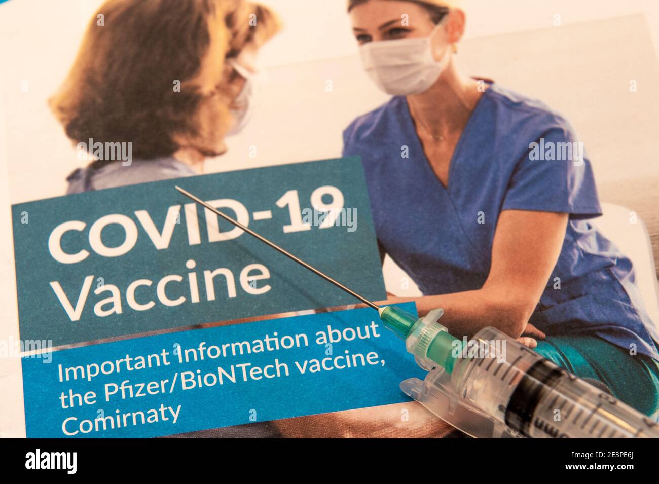 Jeringa y folleto informativo COVID-19 como parte del COVID-19 vacuna sobre fondo blanco Foto de stock