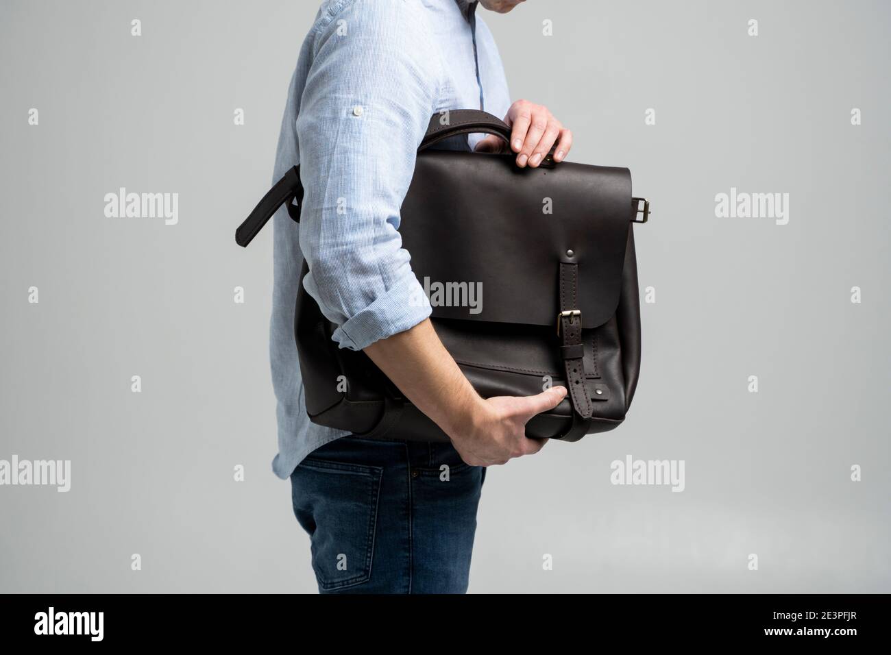Bolso de cuero marrón para hombre para documentos y portátil sostiene por  hombre en una camisa azul y jeans con un fondo blanco. Satchel, piel de  hombre Fotografía de stock - Alamy