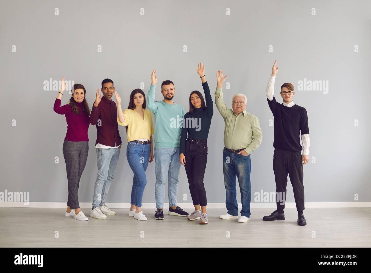 Grupo de personas multirraciales felices levantándose las manos votando una buena sugerencia Foto de stock