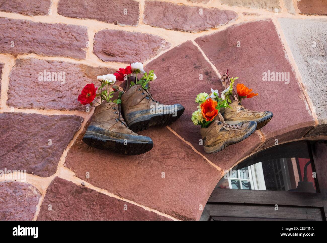 Viejos zapatos de senderismo usando como maceta de flores colgando casa de  pared de piedra. Senderismo de fondo. Estilo de vida, abandono natural,  viajes, conceptos de consumo sostenible Fotografía de stock -