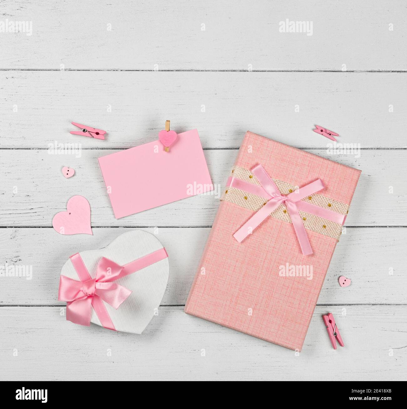 Plantilla de San Valentín de cajas de regalo de color rosa con lazo de  chifón y papel nota sobre el fondo blanco de la mesa de madera, primer  plano de la disposición,