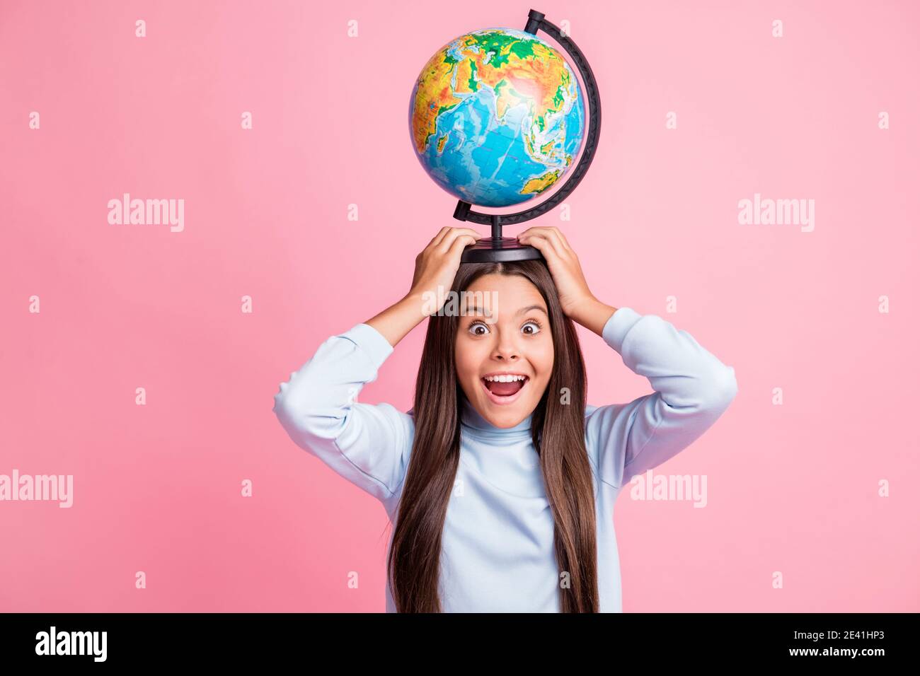 Retrato de una chica muy alegre y divertida llevando globo cabeza con diversión aislada sobre fondo de color pastel rosa Foto de stock