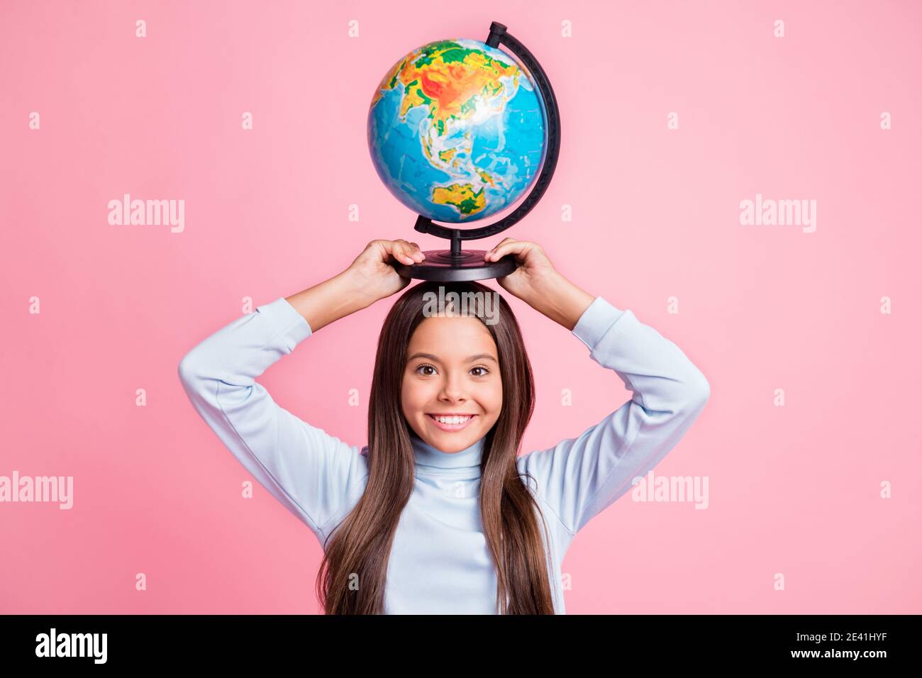 Retrato de encantadora alegre chica graciosa llevando globo lección de cabeza aislada sobre fondo de color pastel rosa Foto de stock