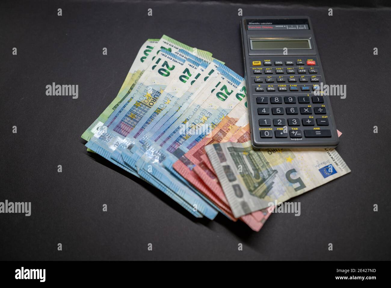 junto a muchos billetes en euros se encuentra una calculadora sobre una base  oscura Fotografía de stock - Alamy