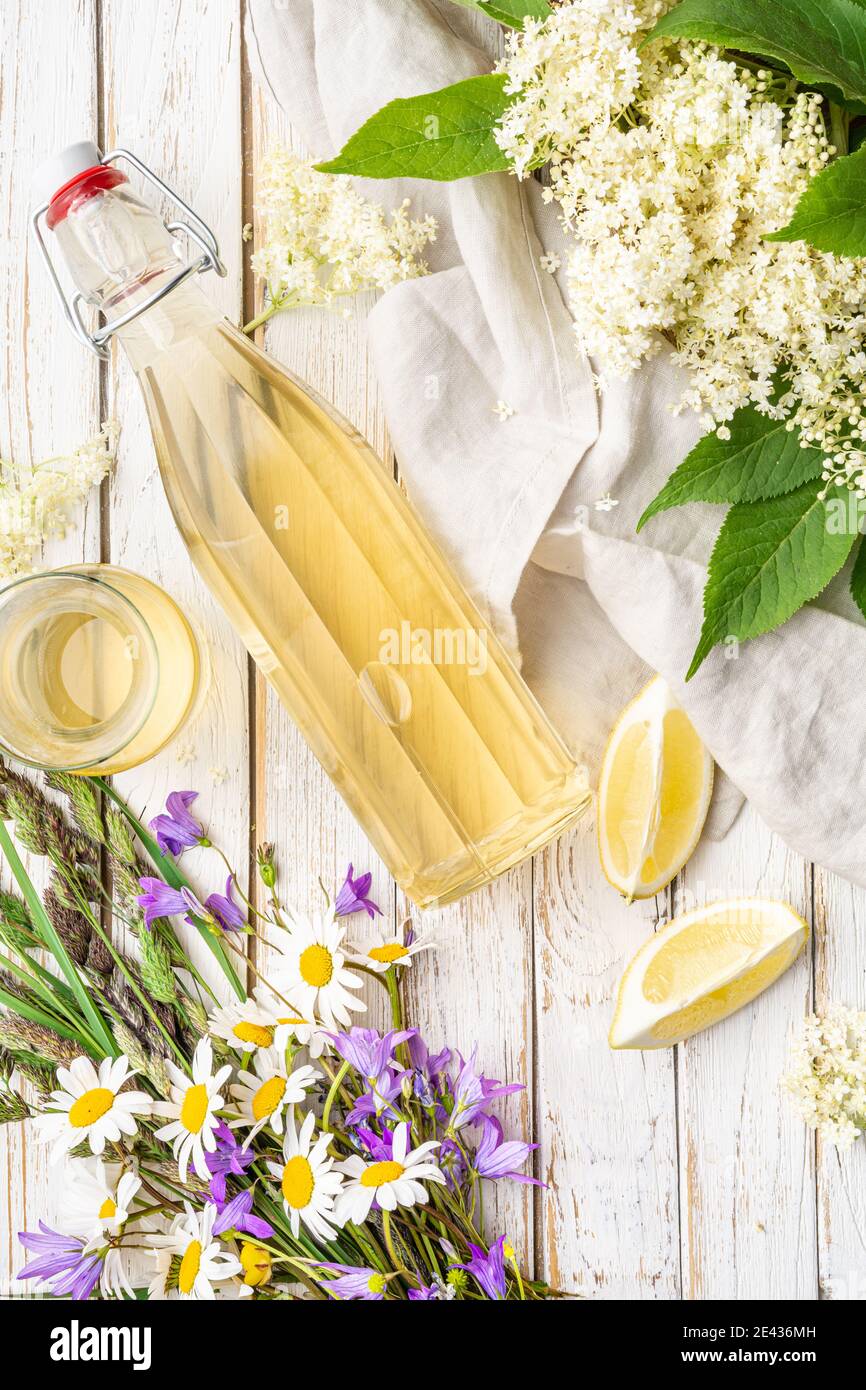 Deliciosa bebida refrescante saludable, jarabe de flor de saúco dulce o cordial en una botella de vidrio sobre fondo rústico de madera Foto de stock