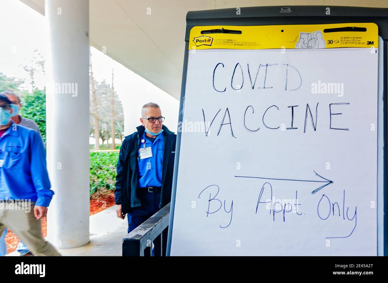 Los trabajadores del hospital pasan por una señal que dirige a los pacientes al centro de distribución de vacunas COVID-19 en el Hospital Providence en Mobile, Alabama. Foto de stock
