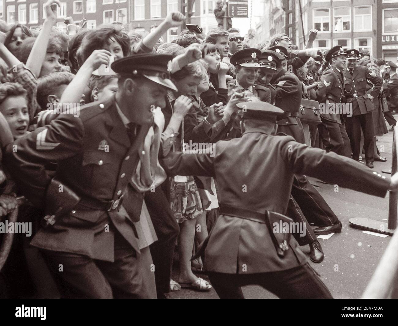 La policía lucha para retener a las multitudes de fans de los Beatles cuando la banda de rock inglesa llegó a Ámsterdam, Holanda del Norte el 5 de junio de 1964. Foto de stock