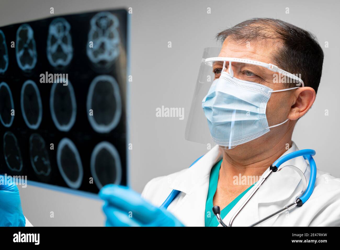 El médico de cabecera en máscara examina la resonancia magnética de la  cabeza en el hospital Fotografía de stock - Alamy