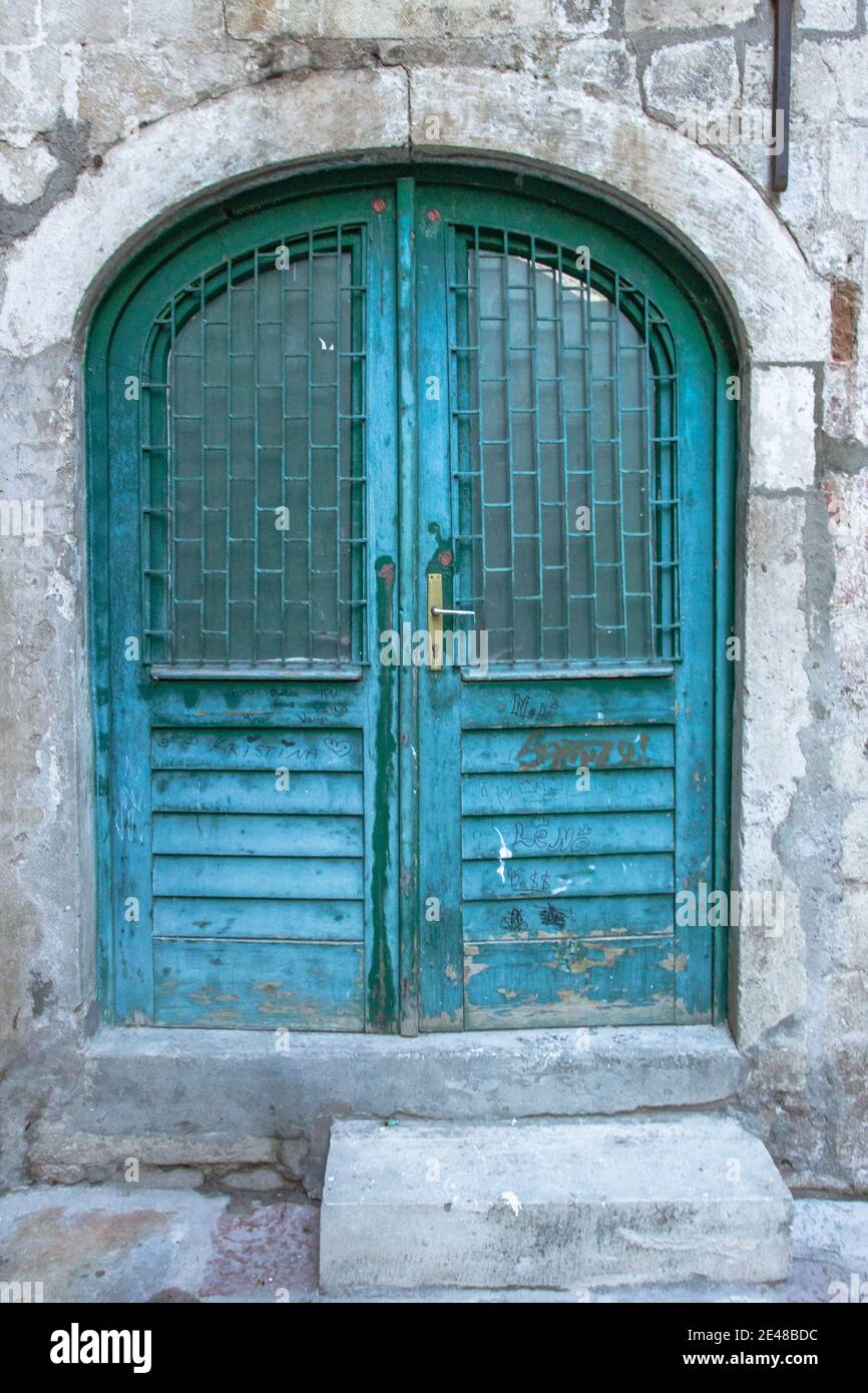 Hermosa puerta pintada de azul vintage. Puerta de madera de grunge azul en pared de ladrillo. Viejas puertas rústicas de madera en Montenegro, Europa. Foto de stock
