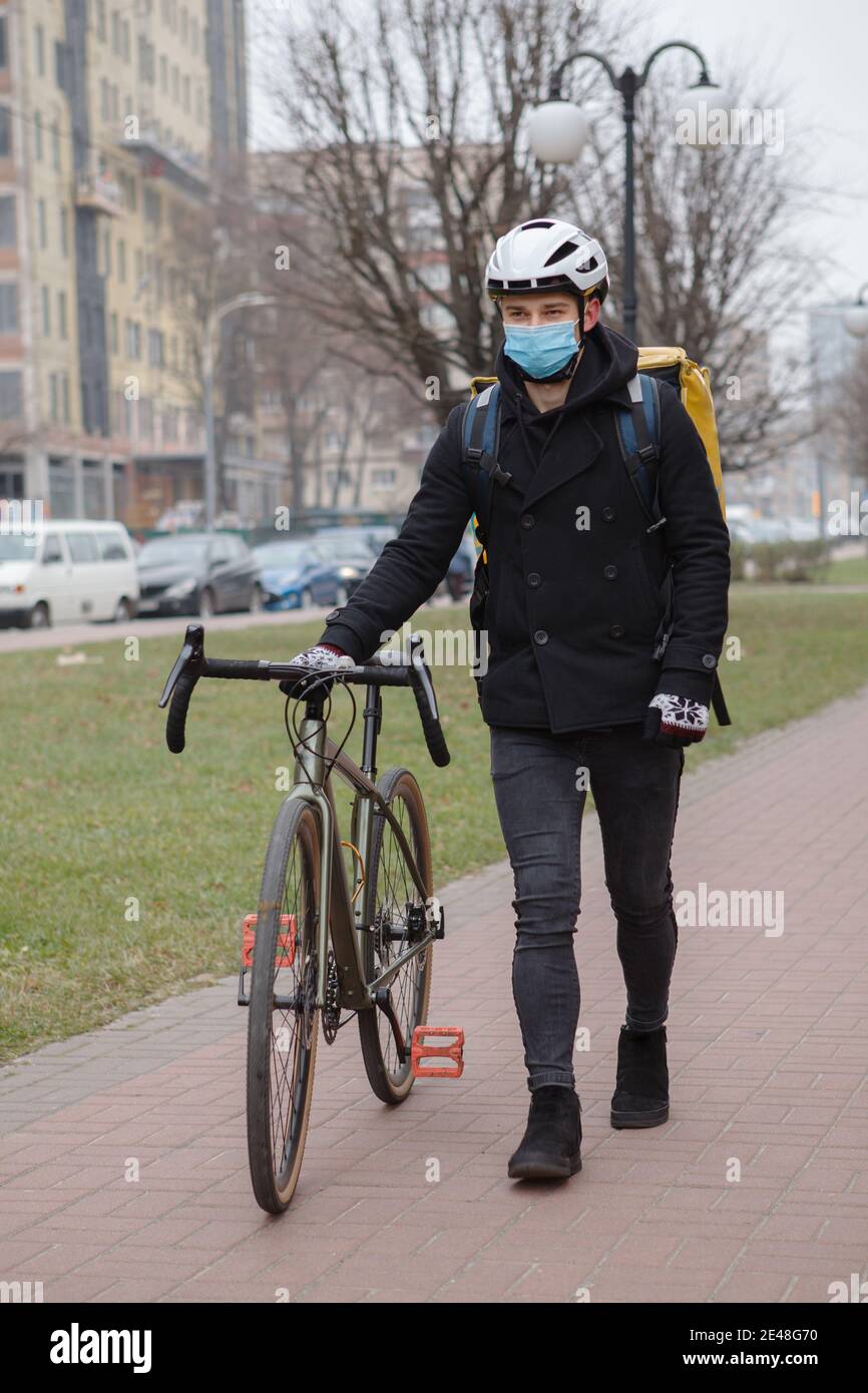 Mensajero masculino con máscara médica, caminando con su bicicleta,  llevando mochila térmica Fotografía de stock - Alamy