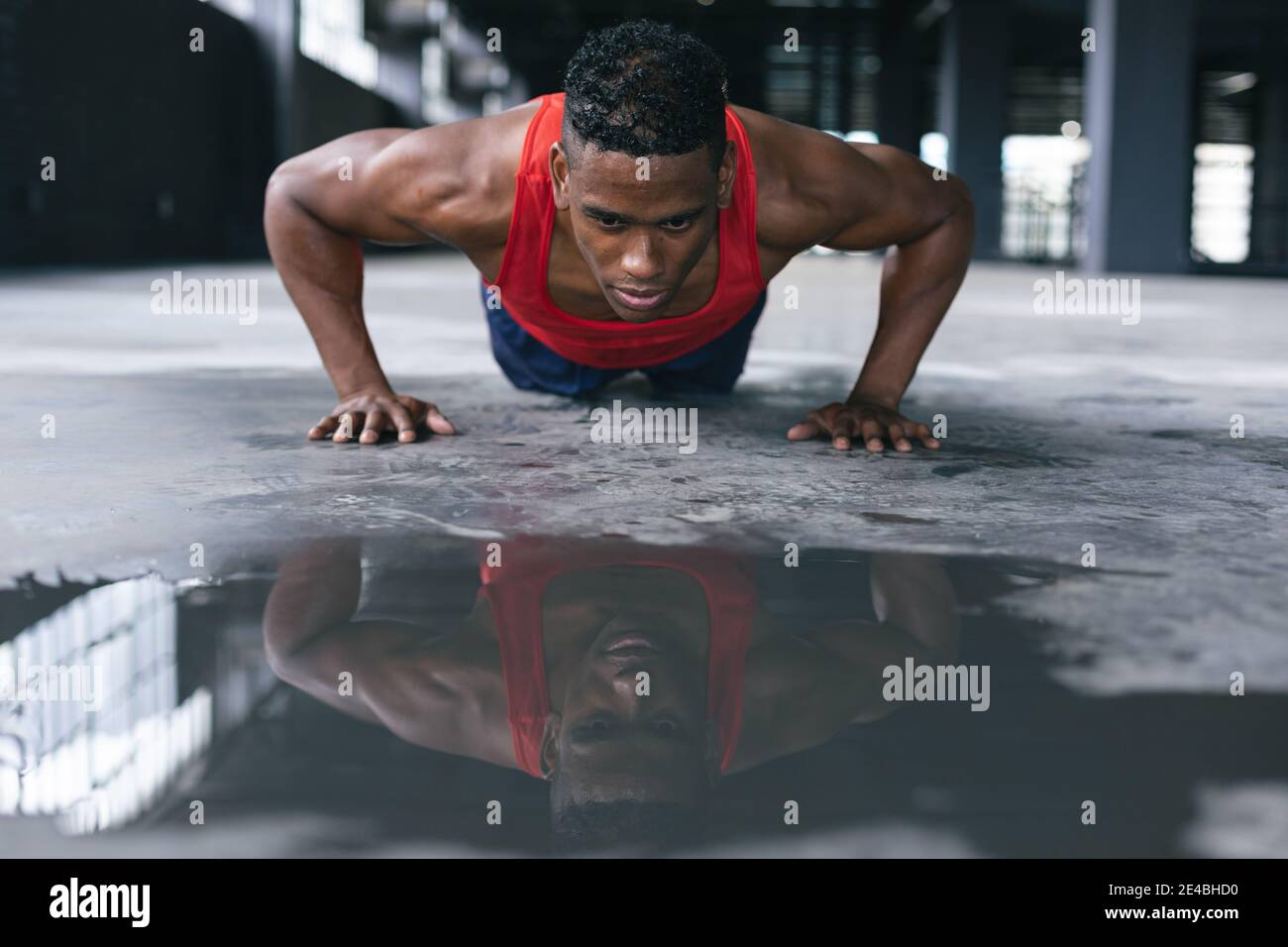 Hombre afroamericano con ropa deportiva haciendo flexiones edificio urbano vacío Foto de stock