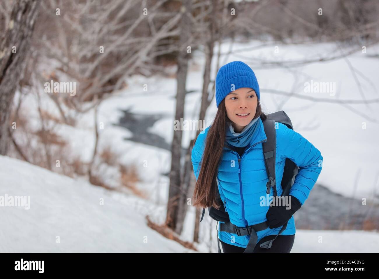 Invierno senderismo mujer asiática excursionista caminar en la ruta de  senderismo de la nieve en el bosque al aire libre. Mochila con chaqueta de  plumón azul y sombrero con mochila Fotografía de