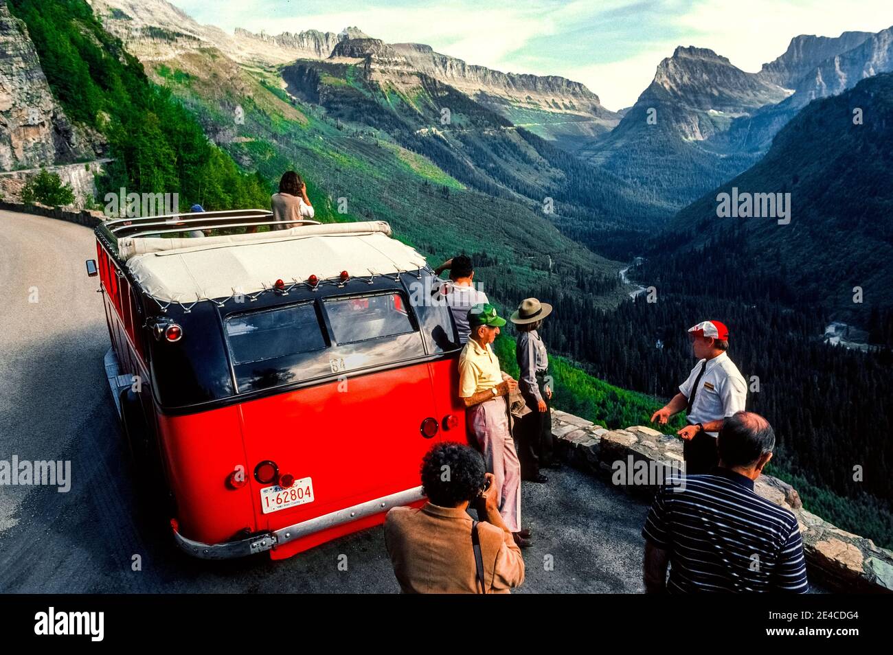 Este autobús turístico rojo de los años 30 ofrece un techo de lona que se abre para proporcionar vistas panorámicas de impresionantes picos de montaña para los turistas en excursiones escénicas a lo largo de la carretera Going-to-the-Sun en el Parque Nacional Glacier en el noroeste de Montana, EE.UU. El vehículo de 17 pasajeros se encuentra entre la flota del parque de 33 autobuses idénticos que se conocen como Red Jammers porque sus conductores "atascan" las marchas al cambiar las transmisiones manuales en las empinadas carreteras montañosas. Todos esos modelos históricos de la White Motor Company N° 706 han sido restaurados a su aspecto original. Foto de stock