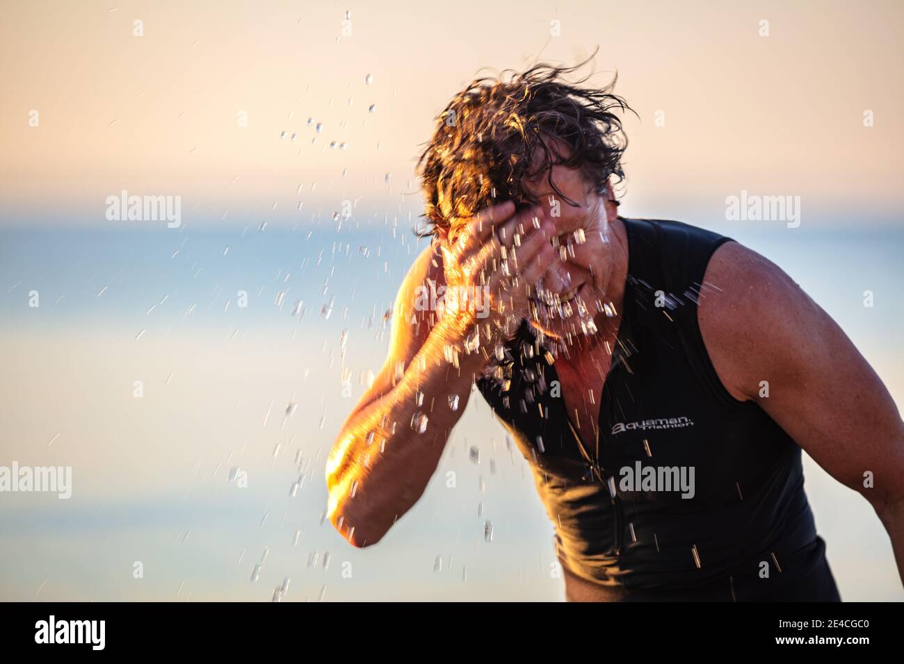 Man 50 plus FIT, con traje de neopreno en el mar. Foto de stock