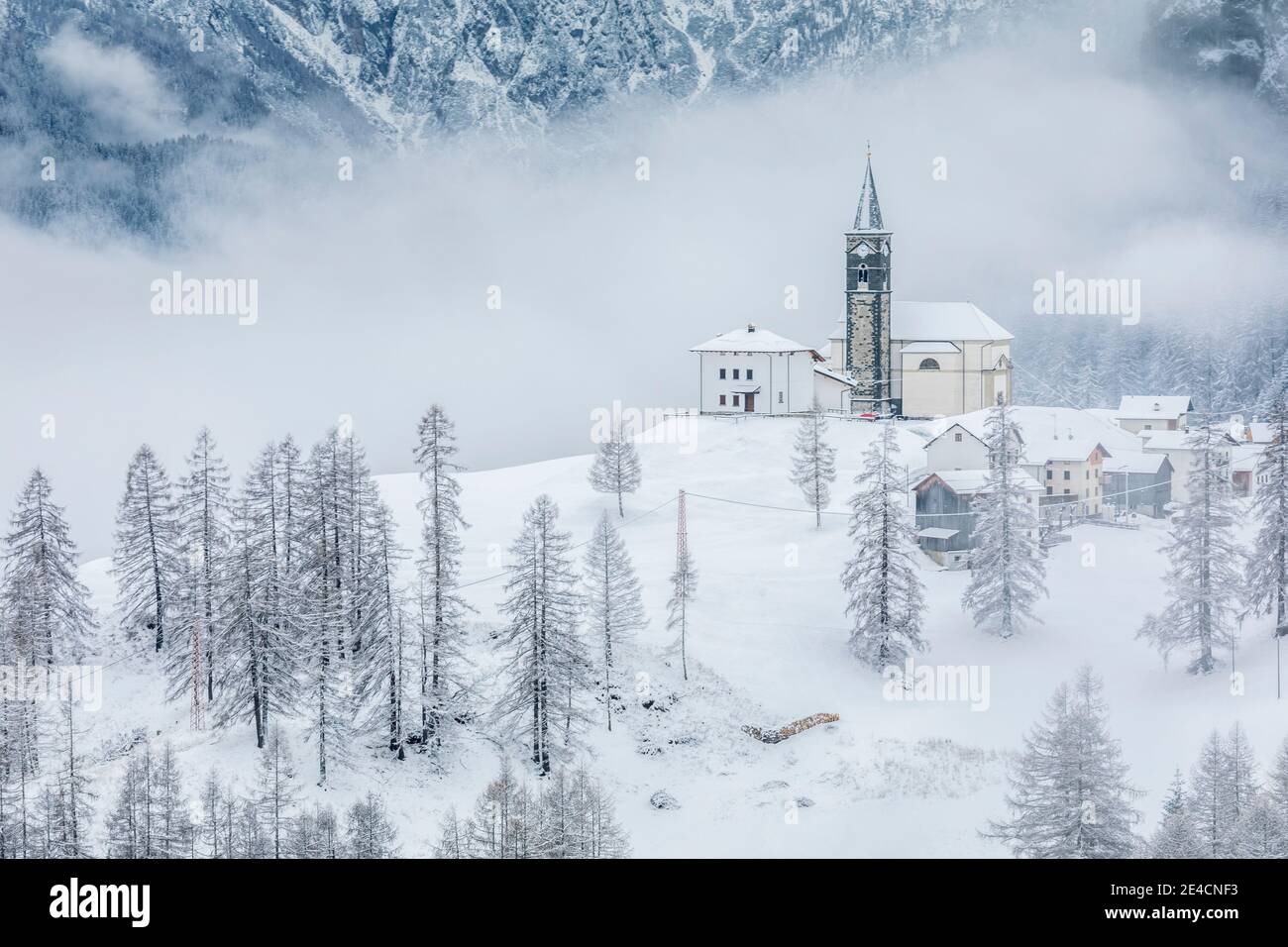 Italia, Véneto, provincia de Belluno, Rocca Pietore, Agordino, el pueblo de laste en invierno con la iglesia de San Gottardo en la colina, Dolomitas Foto de stock