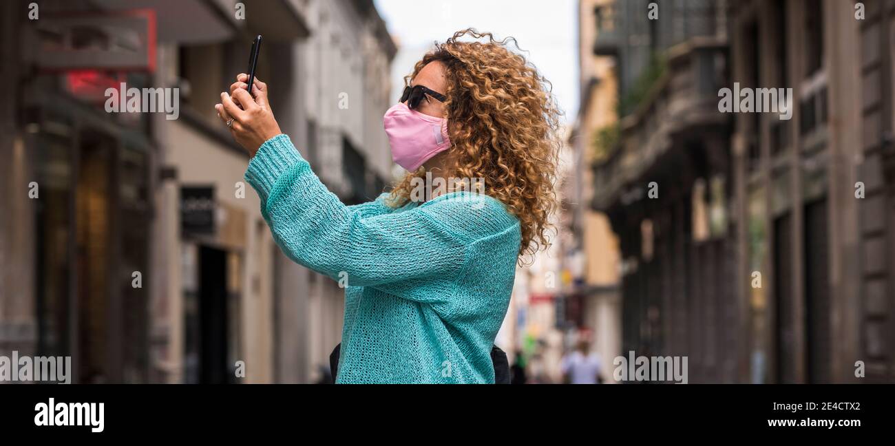 Mujer hacer videollamada llamada con máscara de protección médica para coronavirus covid-19 emergencia de salud en la ciudad - la gente camina y disfrutar de la ciudad protegida del virus de contagio Foto de stock