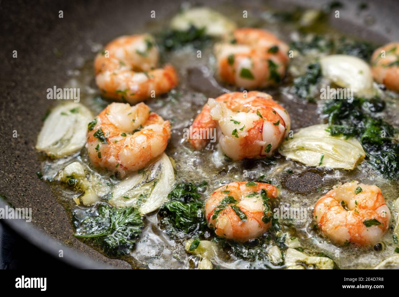 Los camarones saltearon en una sartén con aceite de oliva, ajo y perejil, de cerca con el enfoque seleccionado, profundidad de campo estrecha Foto de stock