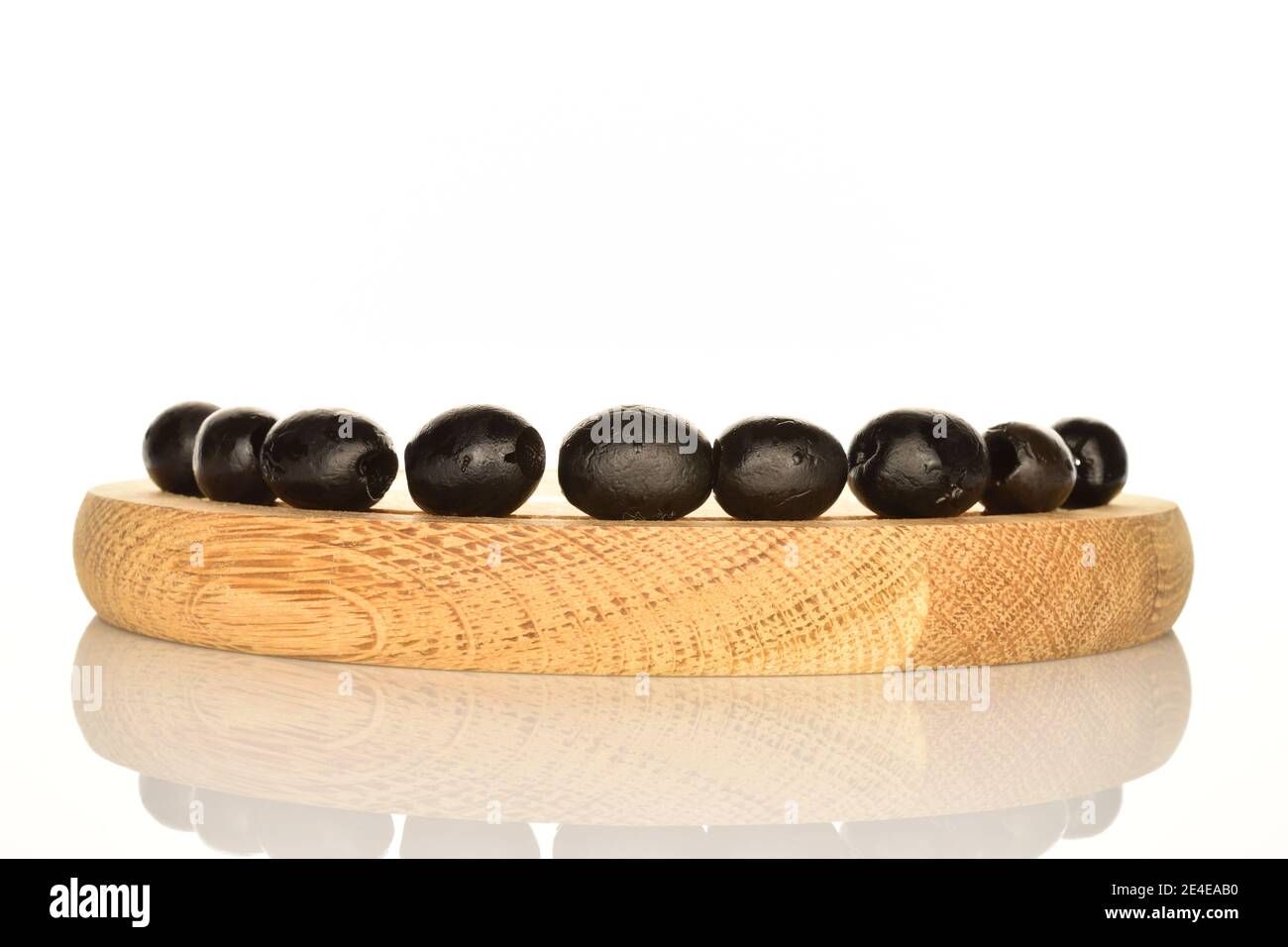 Unas cuantas aceitunas aromáticas enlatadas negras enteras se encuentran  sobre un soporte redondo de madera, sobre un fondo blanco Fotografía de  stock - Alamy