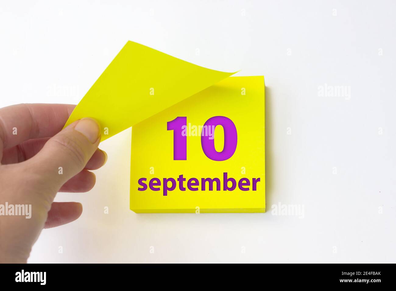 10 de septiembre. Día 10 del mes, fecha del calendario. La mano rasga de la hoja amarilla del calendario. Mes de otoño, concepto de día del año Foto de stock