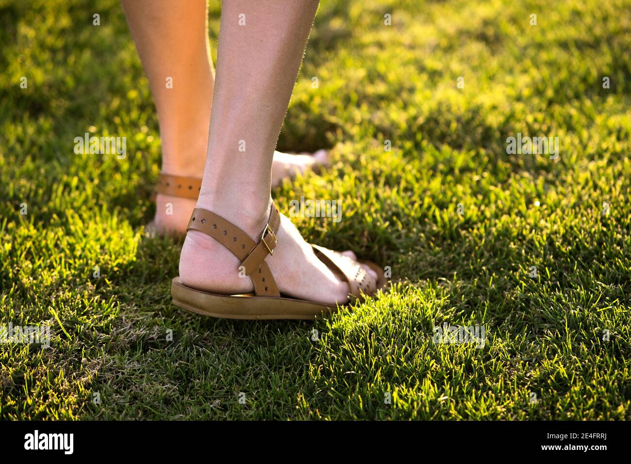 Barefoot mujer con sandalias en vestido blanco sobre el césped en verano  Fotografía de stock - Alamy