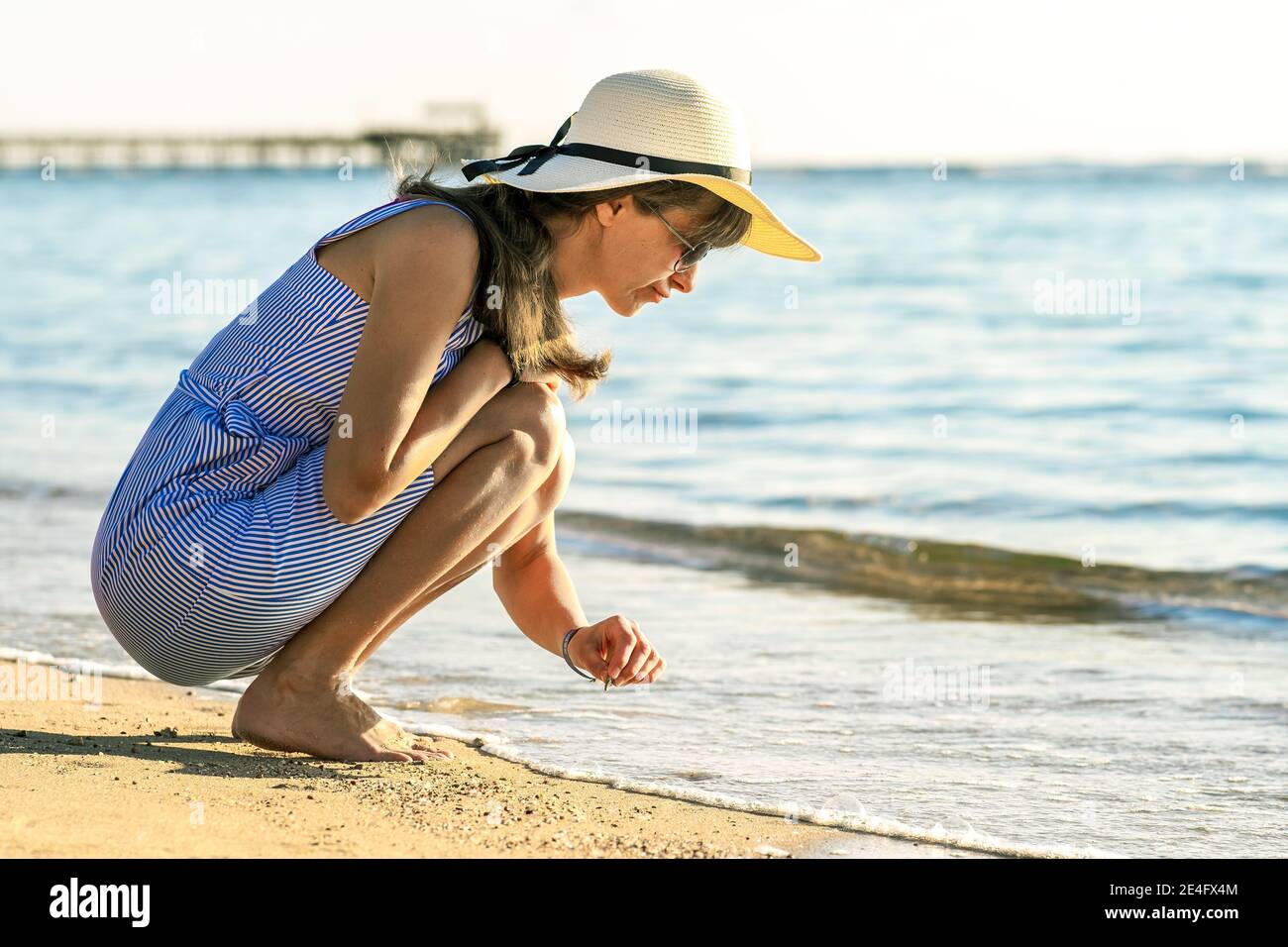 Mujer joven en ropa de verano escribiendo algo la arena de la playa de mar Fotografía de stock - Alamy