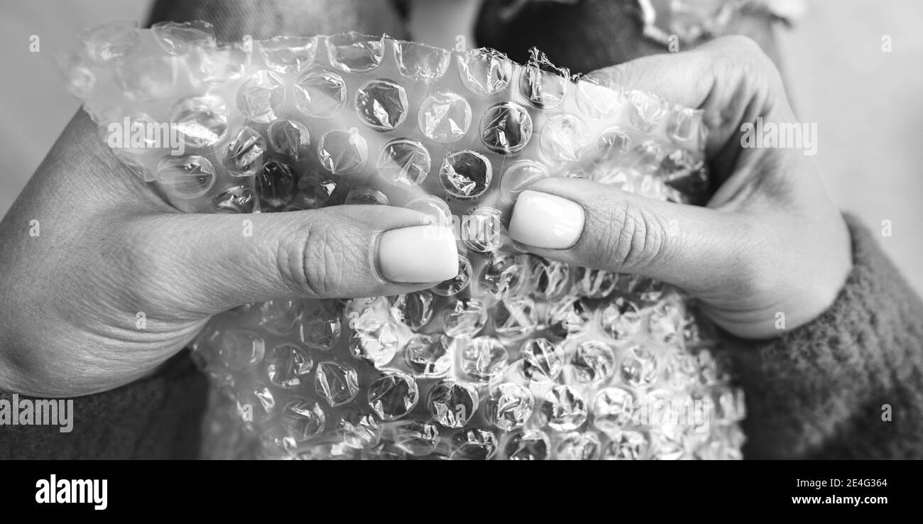 Mujer manos haciendo estallar burbujas en la envoltura de burbujas. Concepto de antiestrés, relajación Foto de stock