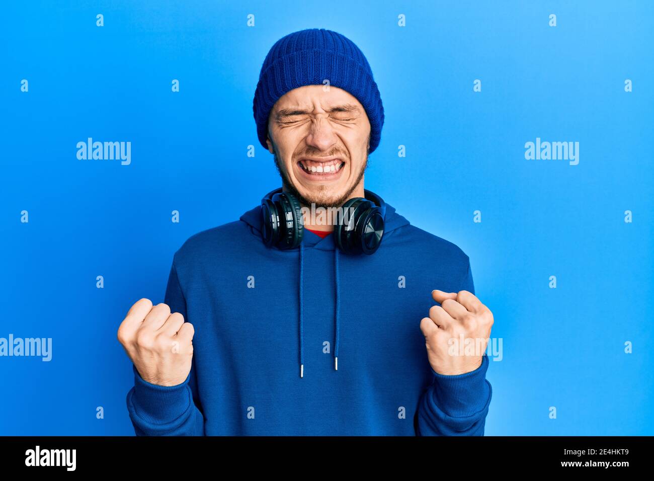 Joven hispano vestido con sudadera y auriculares muy feliz y