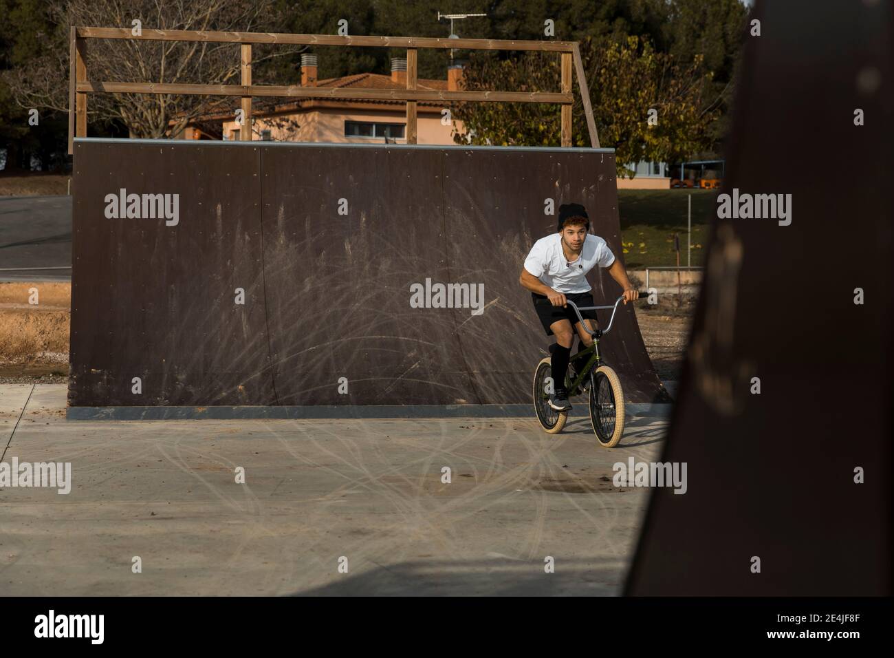 Hombre joven en bicicleta por rampa en el parque de bicicletas Foto de stock