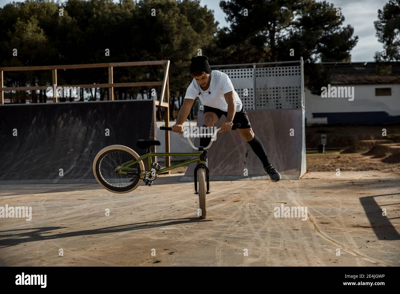 Hombre joven haciendo acrobacias con bicicleta en el parque de bicicletas Foto de stock