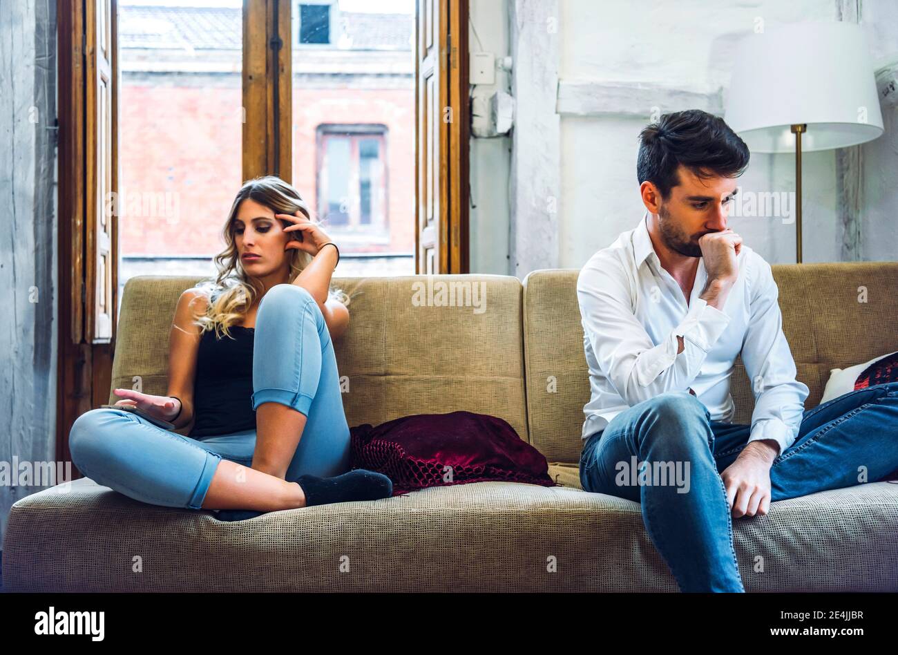 Una pareja sentada en el sofá y enojada después de pelear Foto de stock