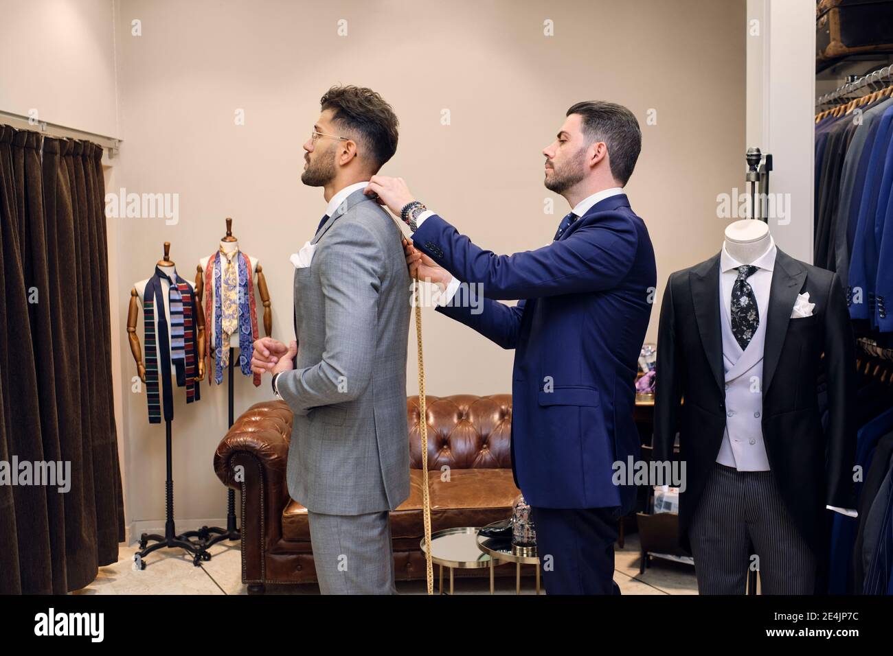 Sastre en su tienda de ropa de hombre tomando las medidas de los clientes  para el traje Fotografía de stock - Alamy
