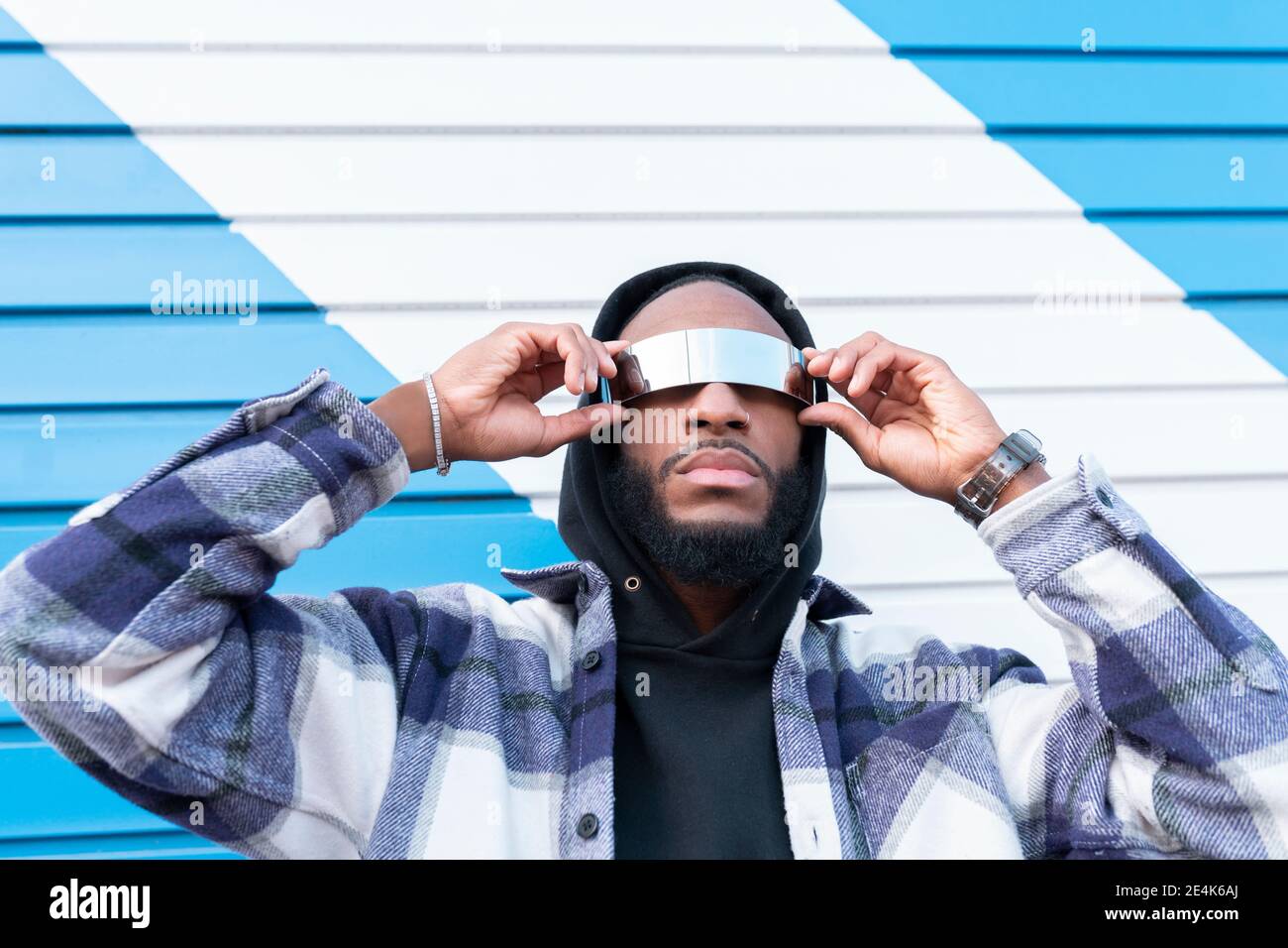 Joven rapero masculino con los brazos levantados usando gafas de sol contra  corrugado hierro Fotografía de stock - Alamy