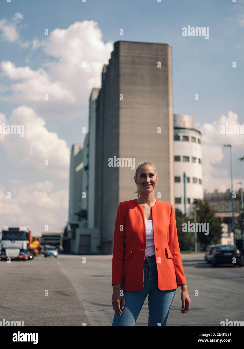 Feliz mujer de negocios de pie en la calle en el distrito industrial Foto de stock