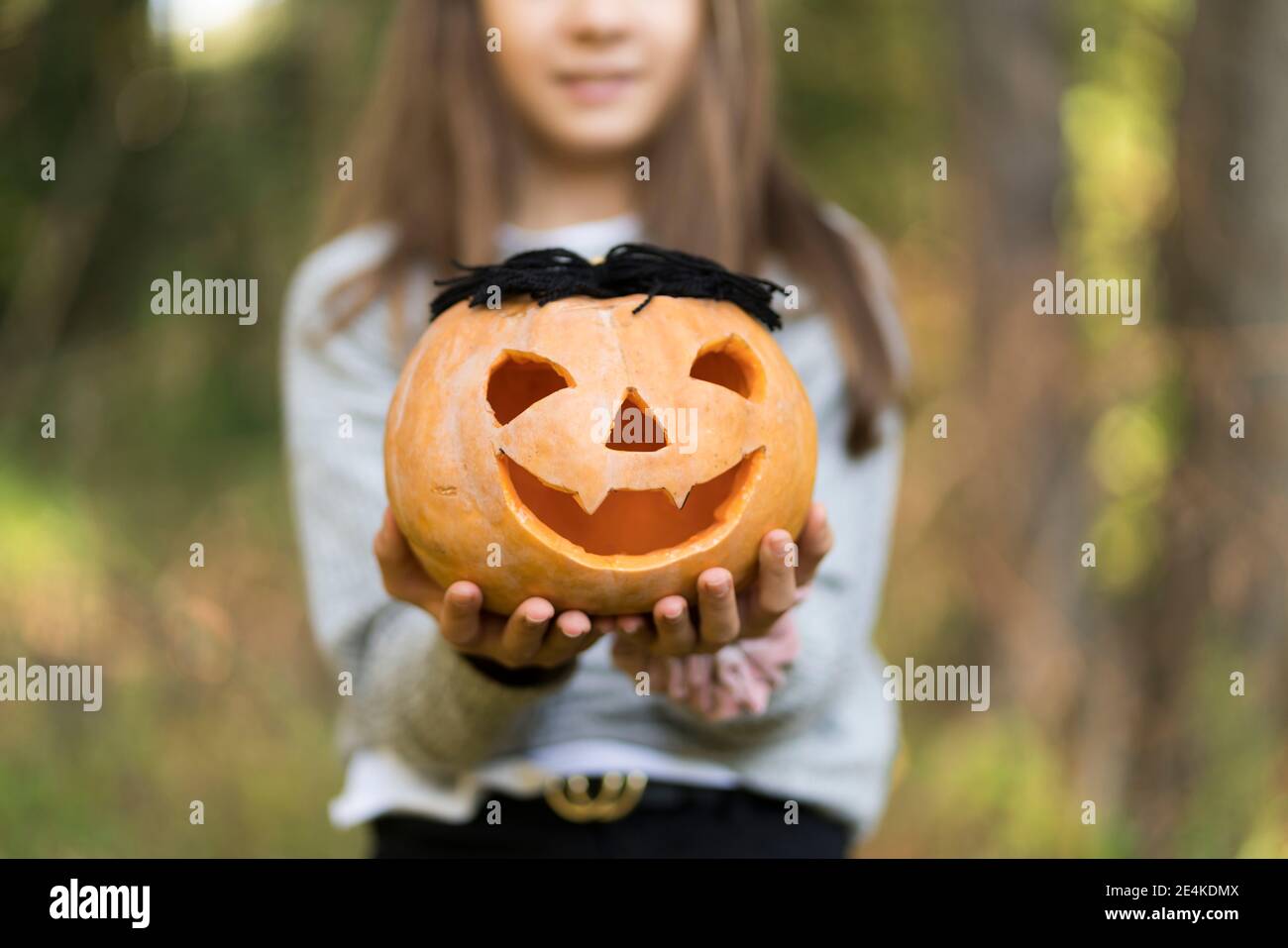 Chica sosteniendo calabaza de Halloween mientras estaba parado en el parque Foto de stock