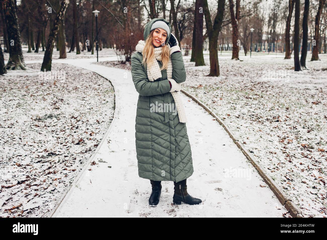 Moda invierno. Mujer joven con abrigo largo bufanda, sombrero, manoplas y botas en el parque nevado. Ropa moderna de stock - Alamy