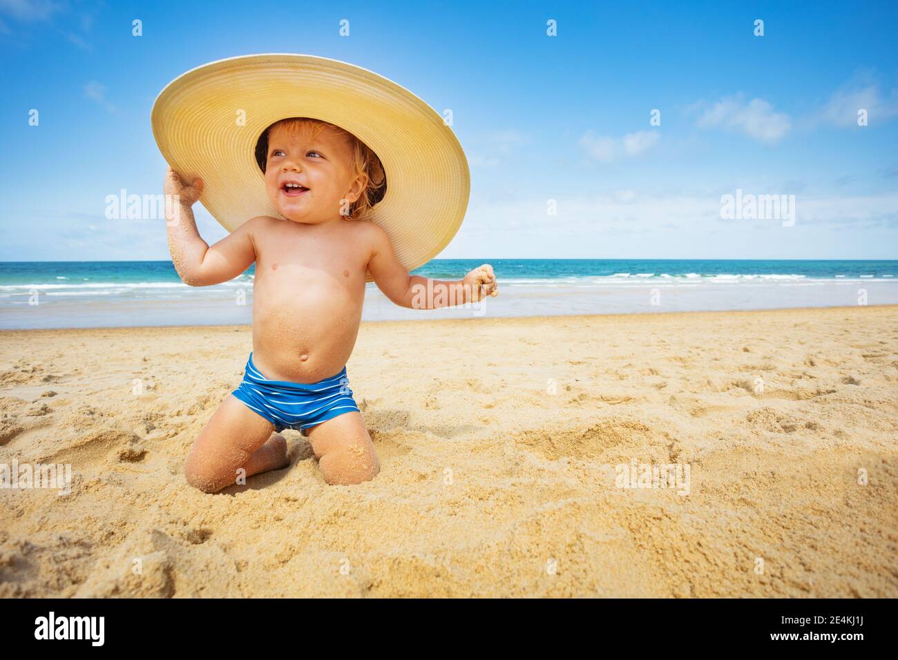 Podrido bolita Cuota Un niño pequeño y feliz sentado en la playa con grande sombrero de paja  sobre fondo de mar Fotografía de stock - Alamy