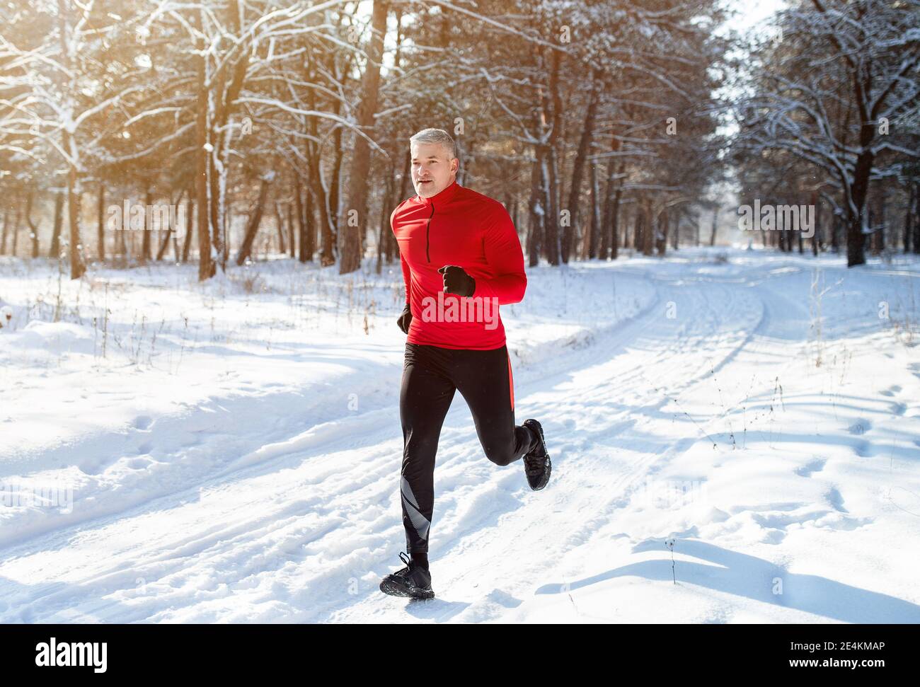 Hombre maduro atlético en jogging de ropa deportiva en el parque de invierno nevado. Corredor senior sano al aire libre en clima frío de stock - Alamy