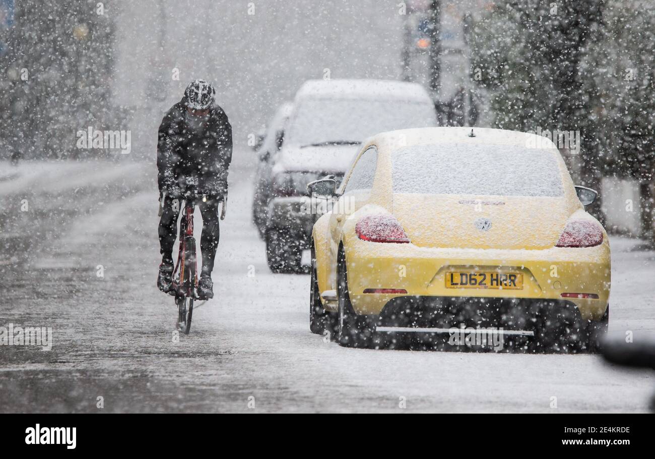Un ciclista negocia la carretera nevada en Kew, al suroeste de Londres, después de que las franjas del Reino Unido se despertaran con nieve y hielo esta mañana, con incluso la capital recibiendo un polvo de blanco. Foto fecha: Domingo 24 de enero de 2021. Foto de stock