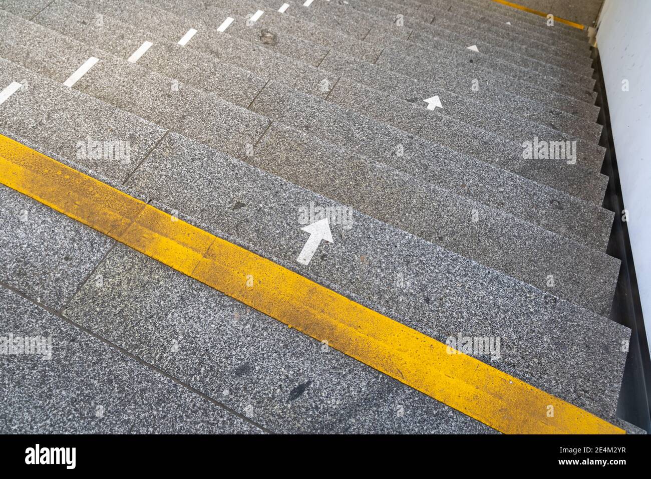 Marcas de flecha en las escaleras de un edificio público para guiar a la gente debido a las medidas covid-19. Líneas para mantener a los peatones a una distancia segura Foto de stock